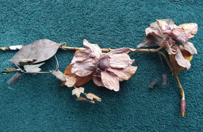 Um caule floral rústico com flores secas em um tapete verde.