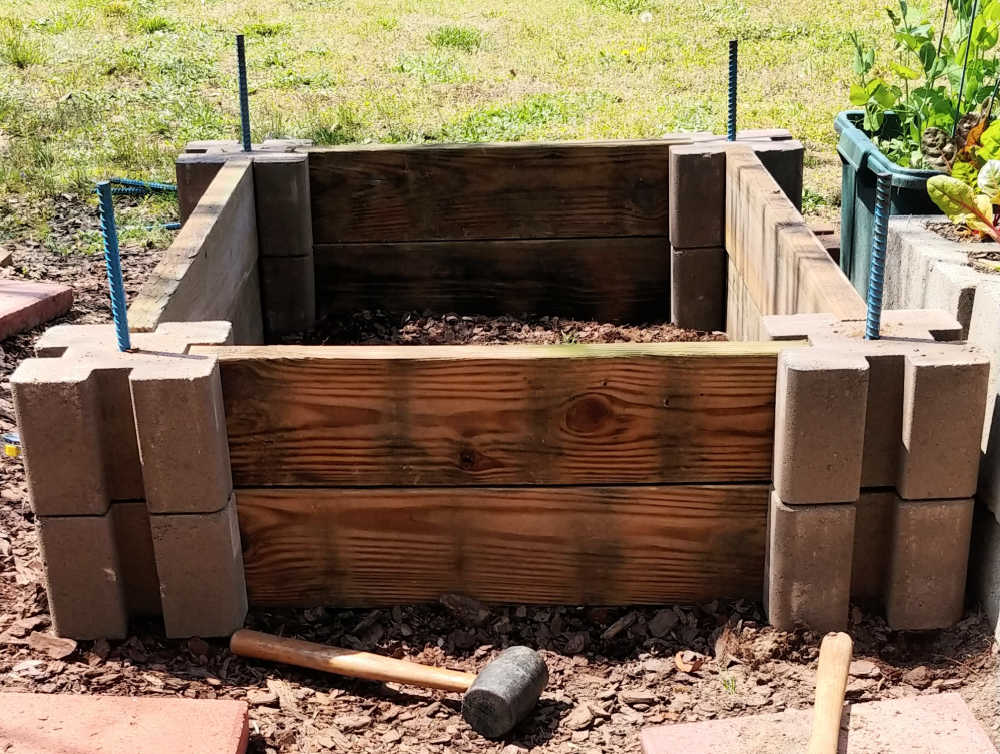 Uma estrutura de cama de jardim de bloco de cimento e madeira com rebar para estabilizar a estrutura.