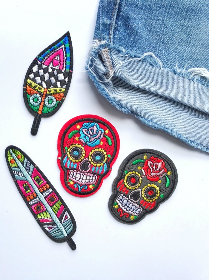 patches de caveira e pena Padrões de ponto cruz de Halloween - Patches bordados ao lado de um par de shorts jeans