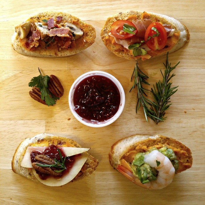 Aperitivos de crostini em uma tábua de madeira com alecrim, nozes e molho.