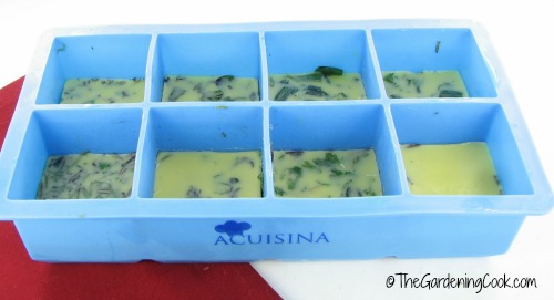 Ervas frescas congeladas em manteiga em formas de gelo de silicone.