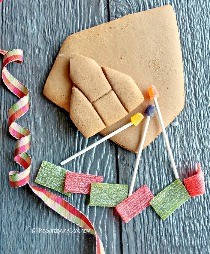 Fita, doces, pedaços de gengibre e postes de luz de gelatina sobre uma tábua de madeira.