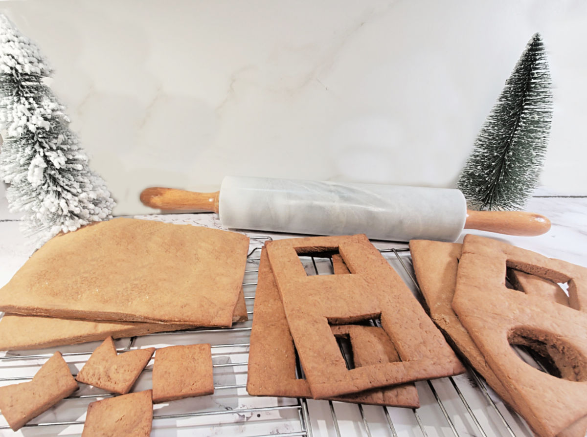 Peças de uma casa de gengibre caseira esfriando em grades, prontas para montar e decorar.