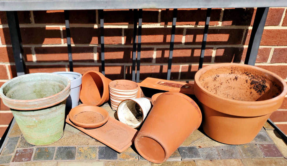 Um monte de vasos e pratinhos de barro sujos e rachados que precisam ser limpos e higienizados no início da primavera.