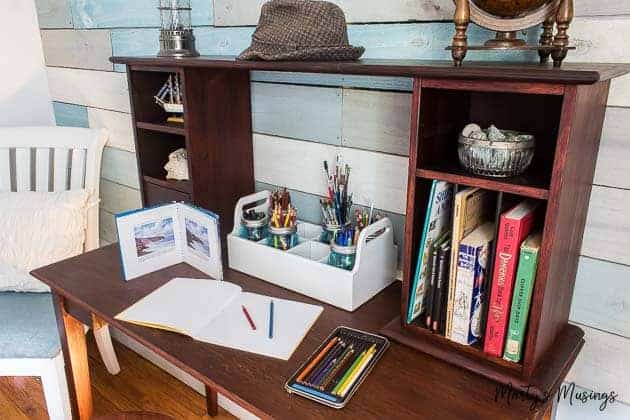 Mesa de trabalho de mogno com material de desenho e livros