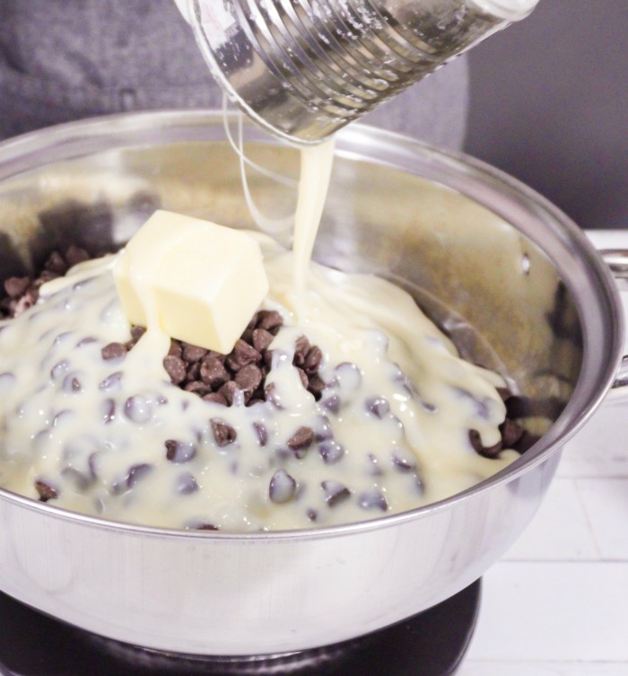 Fazendo fudge. Gotas de chocolate, manteiga e leite condensado para fazer fudge.