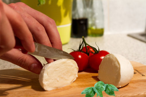 cortando queijo tomate, manjericão e mussarela
