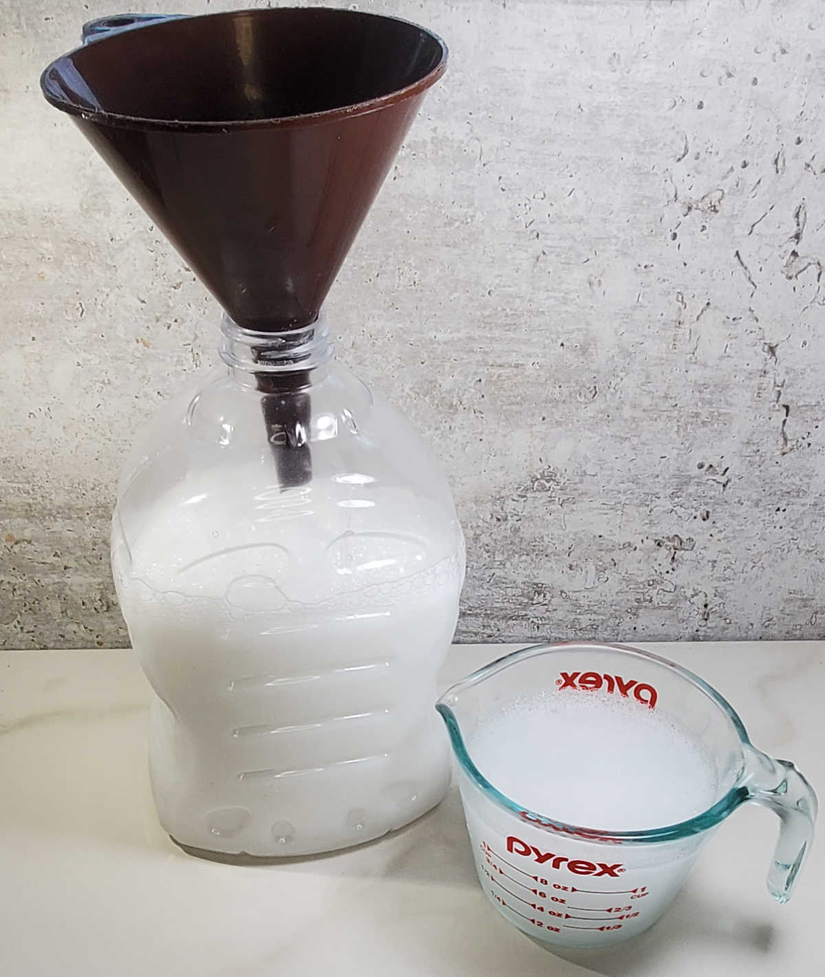 Despeje o sabão líquido em um frasco. Despejando sabão líquido caseiro em um frasco grande com um funil e um copo medidor com bico.