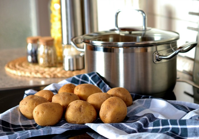 Batatas e uma panela com toalha azul e especiarias.