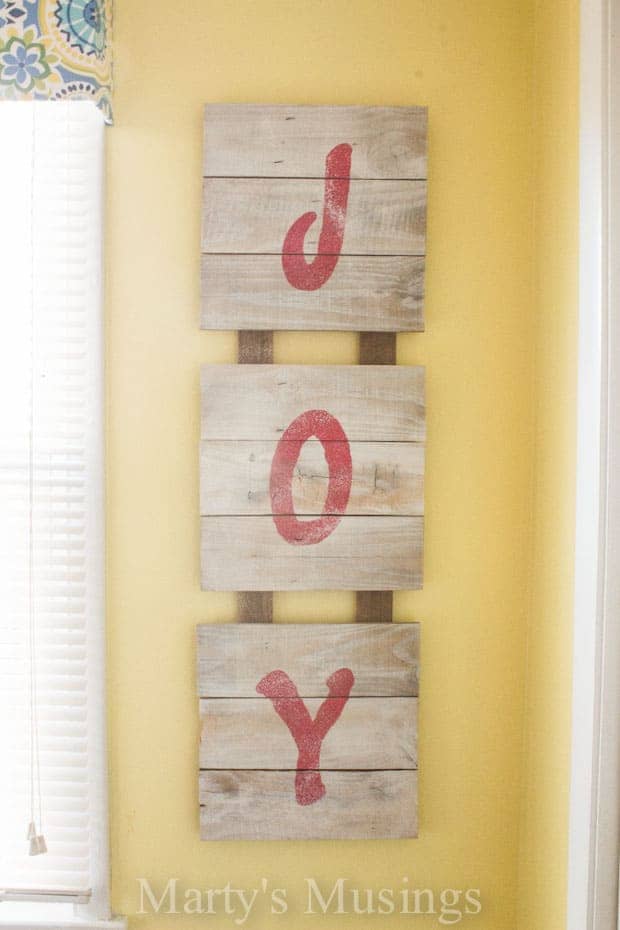 Placa de madeira com JOY em letras em estêncil