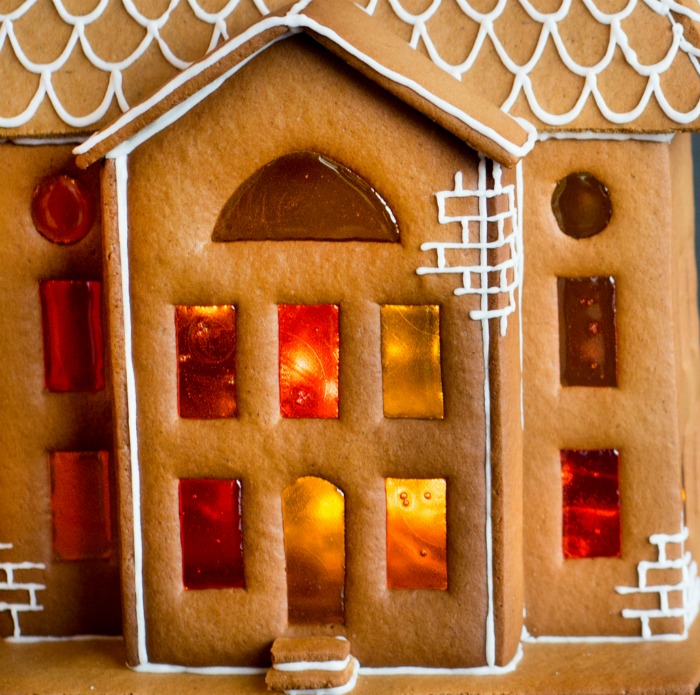 Uma casa de gengibre com glacê branco e doces derretidos usados para fazer janelas de vitral.