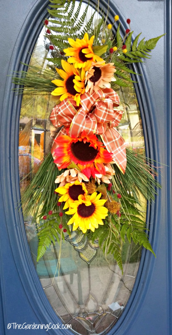 Enfeite de porta de outono pendurado no painel de vidro de uma porta azul.