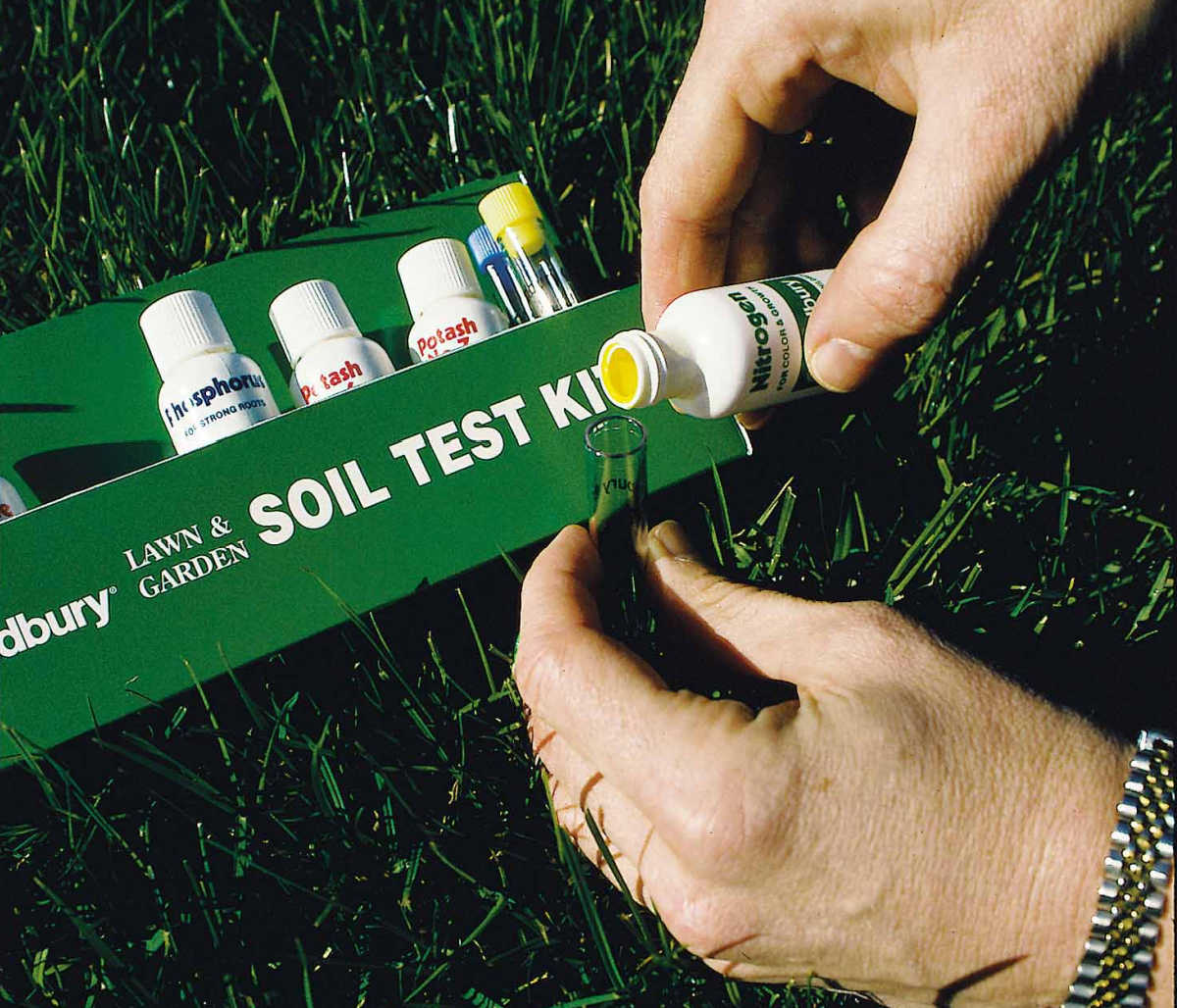 Mãos segurando um kit de teste de solo usado para medir o pH do solo do jardim.