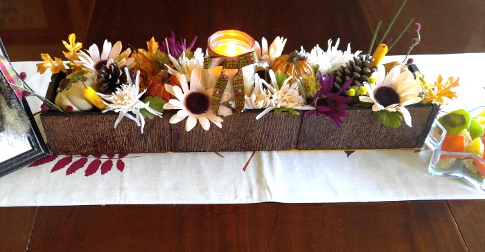 Caminho em uma mesa de madeira com caixa cheia de flores.