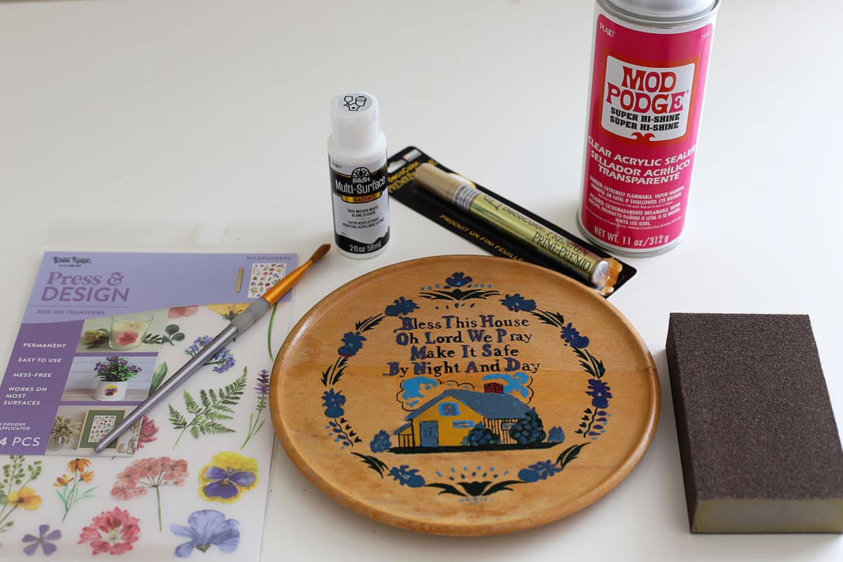 Materiais para reaproveitar uma placa de cozinha de madeira kitsch dos anos 1960. Inclui tinta, selante acrílico e transfers.
