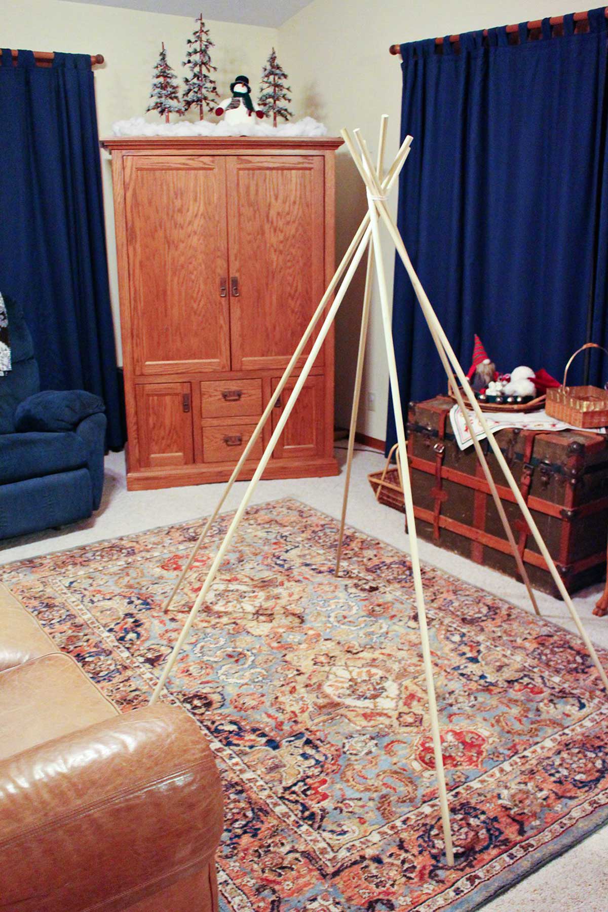 6 bastões de madeira amarrados no topo para criar uma estrutura de tenda em estilo teepee.