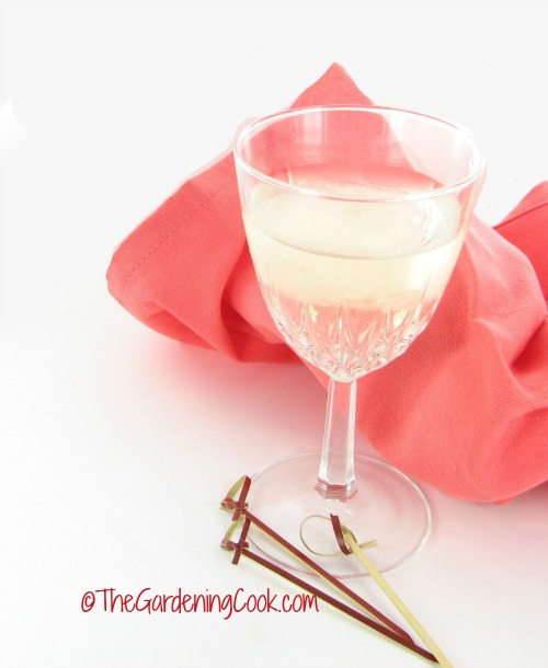 Cubos de vinho congelados em um copo de vinho com canudinhos de coquetel e um guardanapo pêssego.