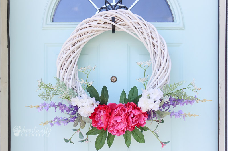 guirlanda de verão em vime branco com flores vibrantes, em porta pastel