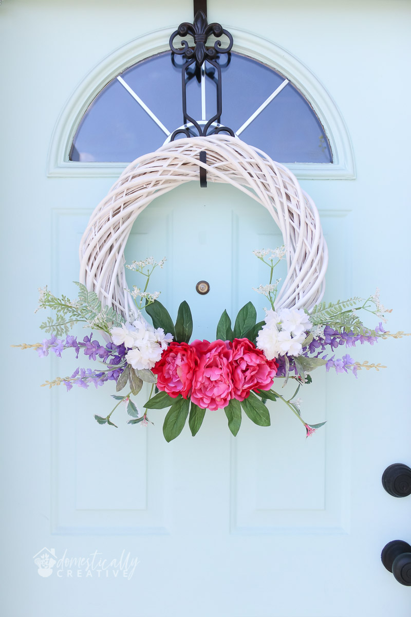 guirlanda de verão em vime branco com flores vibrantes, em porta pastel